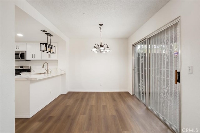 kitchen featuring sink, dark hardwood / wood-style floors, appliances with stainless steel finishes, decorative light fixtures, and white cabinetry