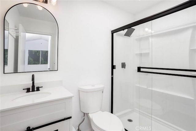 bathroom featuring vanity, a shower with shower door, and toilet