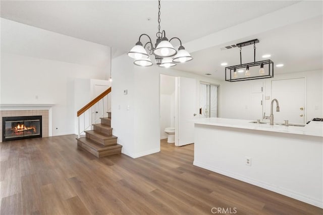 kitchen featuring hardwood / wood-style flooring, a fireplace, sink, and hanging light fixtures