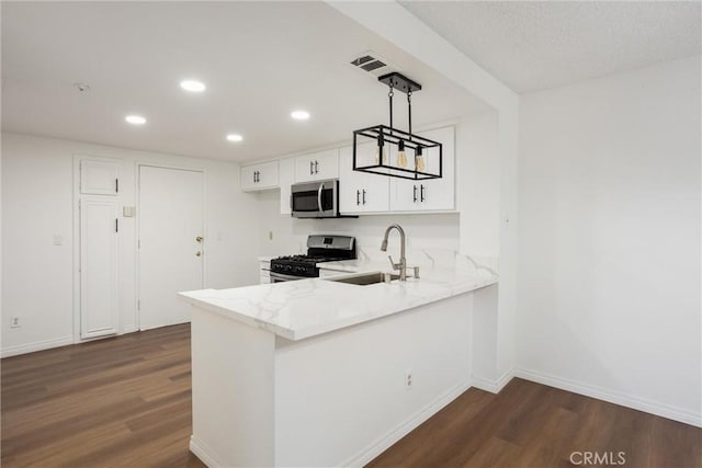 kitchen with sink, dark wood-type flooring, decorative light fixtures, white cabinets, and appliances with stainless steel finishes