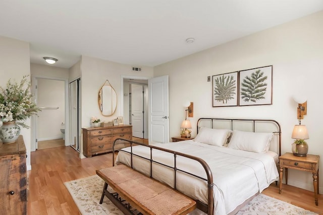 bedroom with ensuite bath and light hardwood / wood-style floors