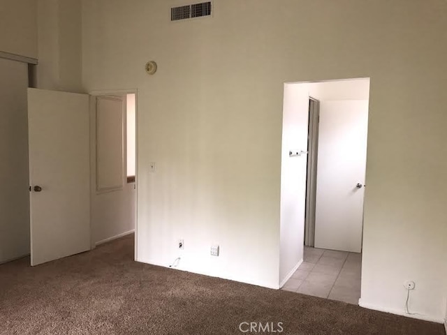 spare room featuring a towering ceiling and light colored carpet