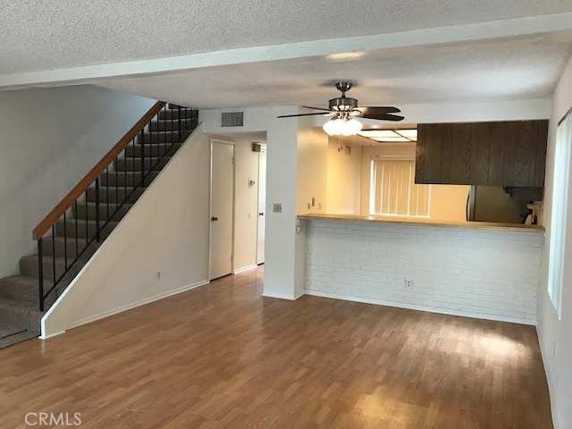 unfurnished living room featuring ceiling fan, wood-type flooring, and a textured ceiling