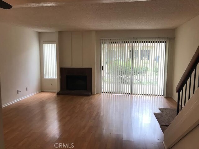 unfurnished living room with wood-type flooring and a textured ceiling