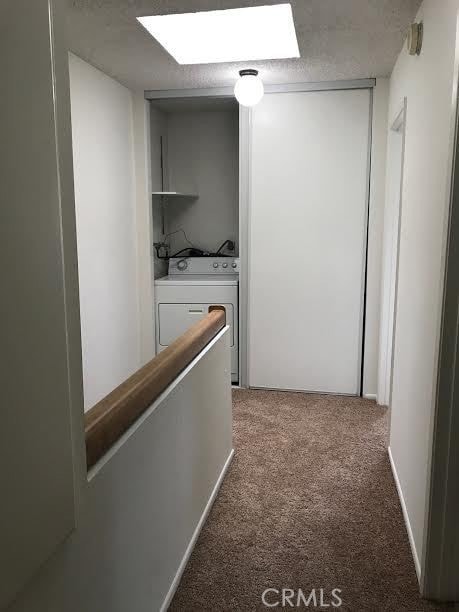 corridor featuring washer / clothes dryer, carpet, and a skylight