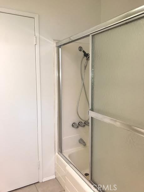 bathroom featuring tile patterned floors and bath / shower combo with glass door