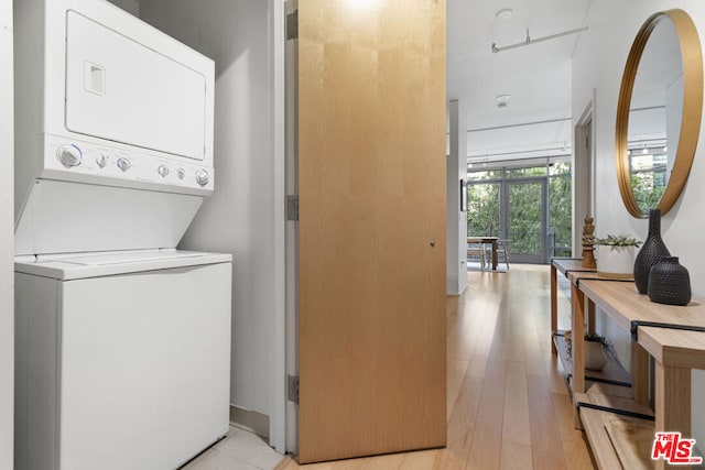 laundry room with light hardwood / wood-style floors and stacked washer / dryer