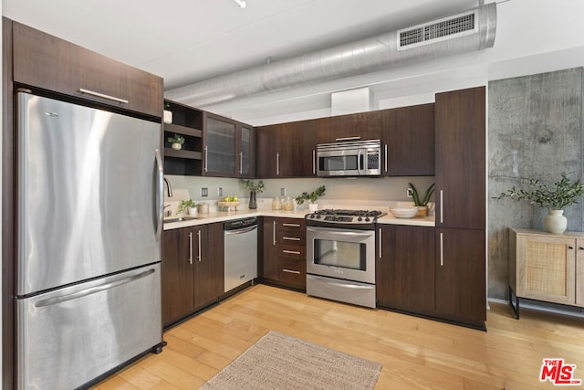 kitchen with appliances with stainless steel finishes, light hardwood / wood-style flooring, dark brown cabinets, and sink