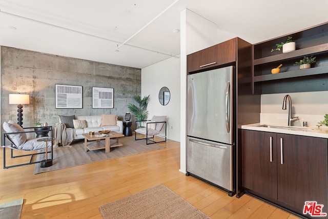 kitchen featuring dark brown cabinetry, light hardwood / wood-style flooring, stainless steel refrigerator, and sink