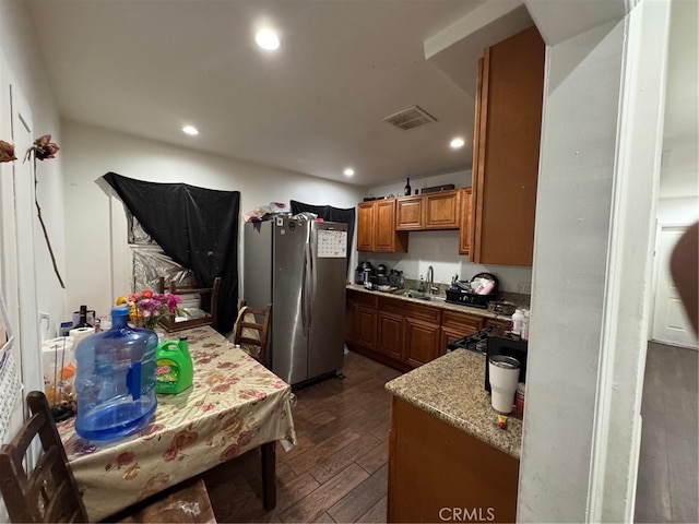 kitchen featuring sink, light stone counters, dark hardwood / wood-style flooring, and stainless steel fridge