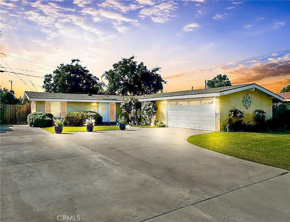 single story home featuring a garage and a yard