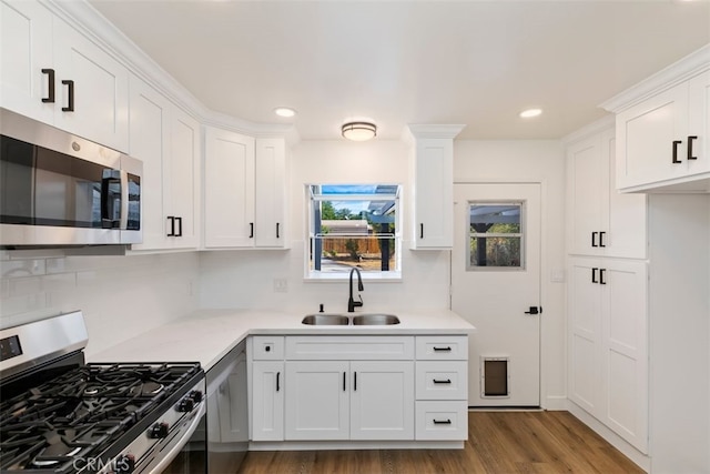 kitchen featuring decorative backsplash, sink, white cabinetry, appliances with stainless steel finishes, and dark hardwood / wood-style flooring