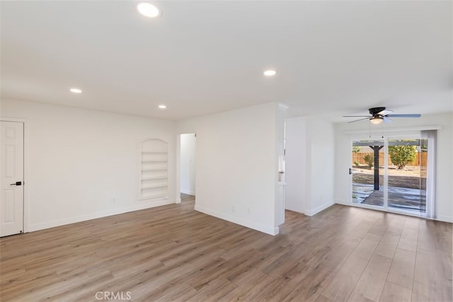 empty room featuring built in shelves, light hardwood / wood-style floors, and ceiling fan