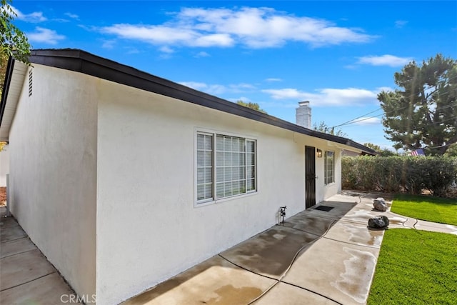 view of side of home featuring a yard and a patio area