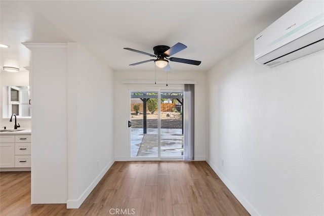 spare room featuring light hardwood / wood-style floors, an AC wall unit, sink, and ceiling fan