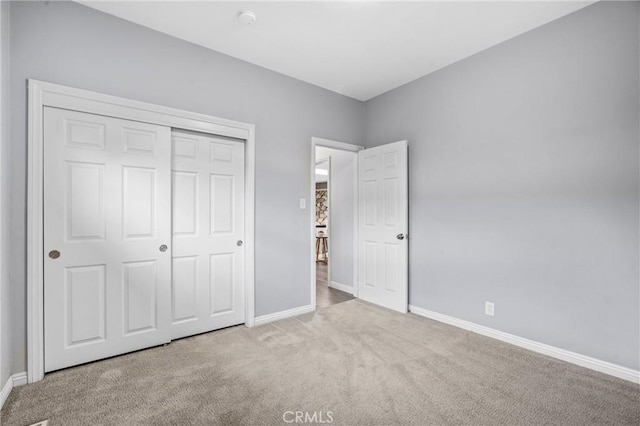 unfurnished bedroom with light colored carpet and a closet