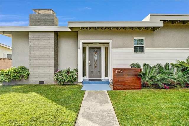 view of exterior entry featuring a yard