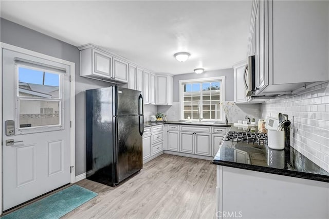 kitchen featuring sink, stainless steel appliances, tasteful backsplash, light hardwood / wood-style flooring, and white cabinets