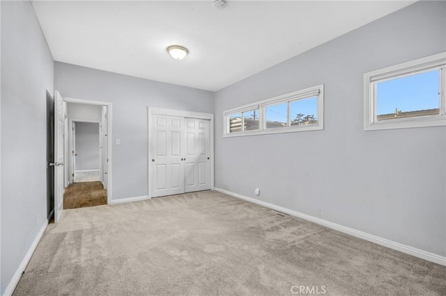 unfurnished bedroom featuring light colored carpet and a closet