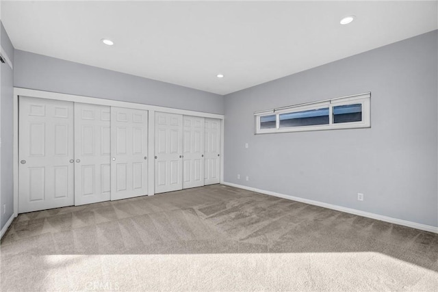 unfurnished bedroom with carpet floors and two closets