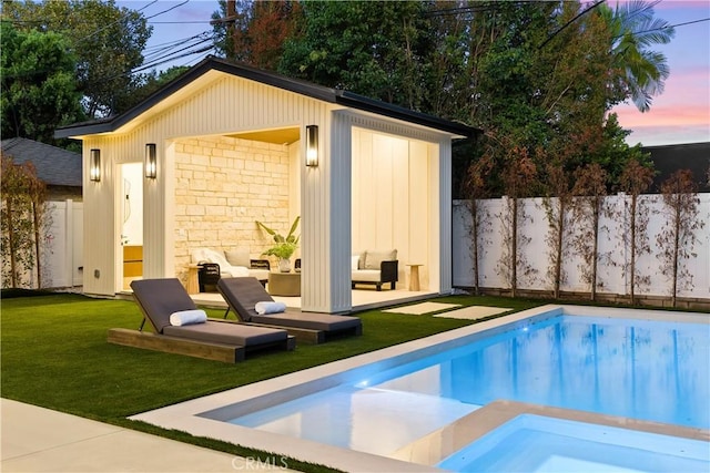 pool at dusk featuring an outbuilding and a yard