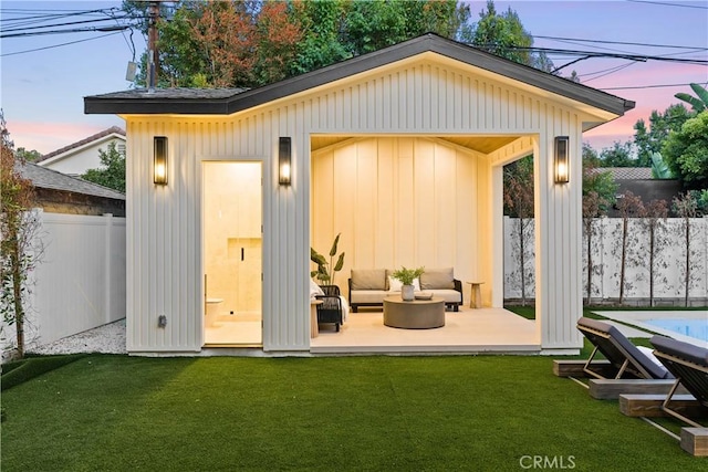 outdoor structure at dusk featuring an outdoor living space and a yard