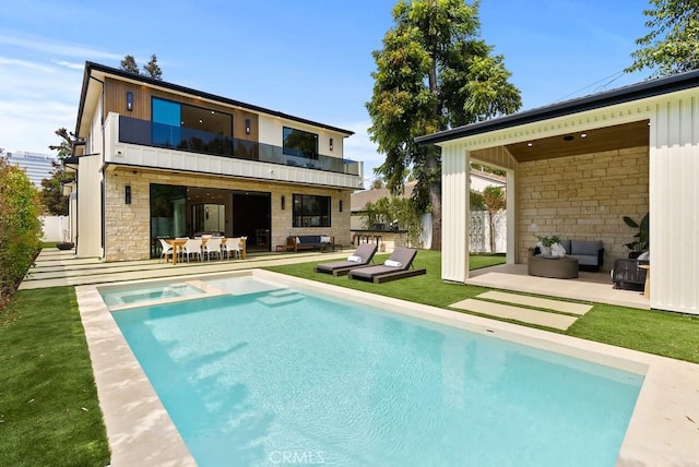 rear view of property with a balcony, a yard, an outdoor hangout area, and a patio