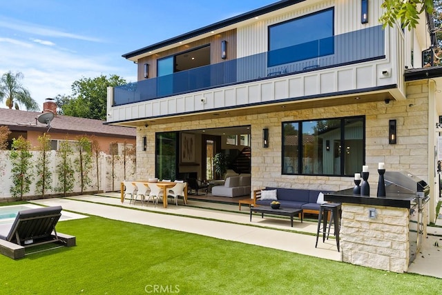 rear view of house with a yard, an outdoor hangout area, a balcony, exterior bar, and a patio