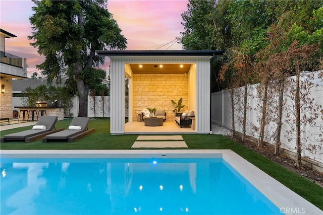 pool at dusk featuring a bar and a yard