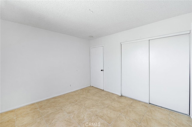 unfurnished bedroom featuring a textured ceiling and a closet