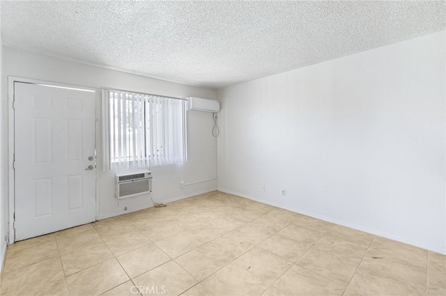 spare room featuring a wall mounted AC, a textured ceiling, and light tile patterned floors