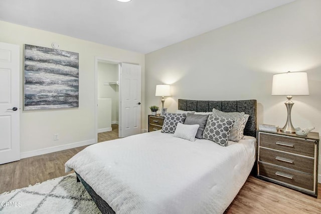 bedroom with a closet, a walk in closet, and light hardwood / wood-style flooring