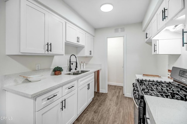 kitchen featuring light hardwood / wood-style flooring, white cabinetry, sink, and gas range