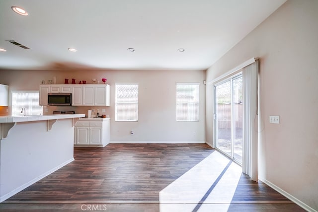 kitchen with a breakfast bar, white cabinetry, and dark wood-type flooring