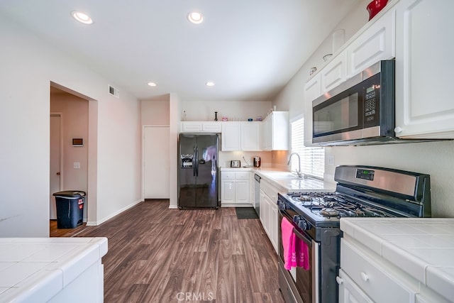 kitchen with tile countertops, dark hardwood / wood-style floors, white cabinetry, and stainless steel appliances