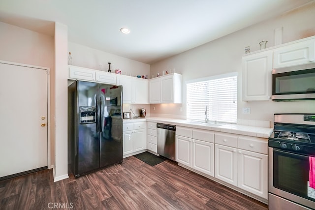 kitchen featuring white cabinets, sink, dark hardwood / wood-style floors, tile counters, and stainless steel appliances