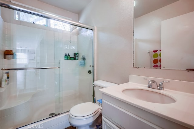 bathroom with a shower with door, vanity, and toilet