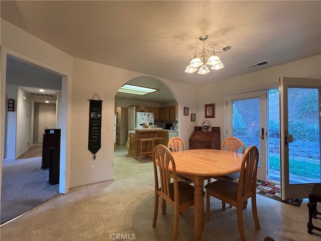 carpeted dining area with a chandelier