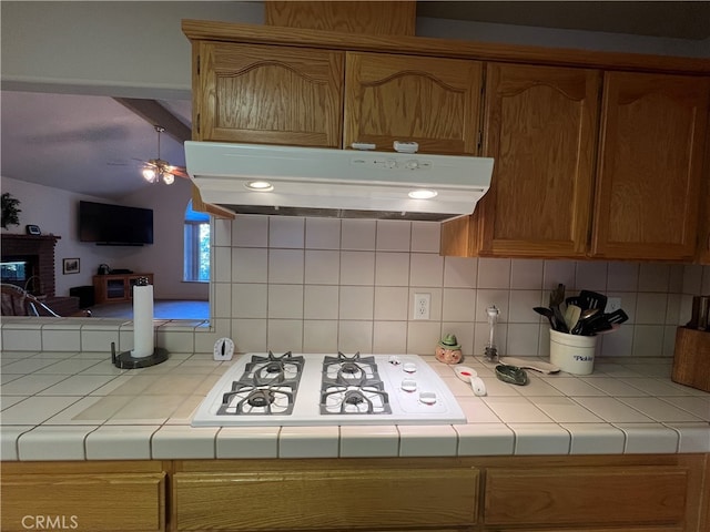 kitchen featuring tile countertops, decorative backsplash, white gas cooktop, and ceiling fan