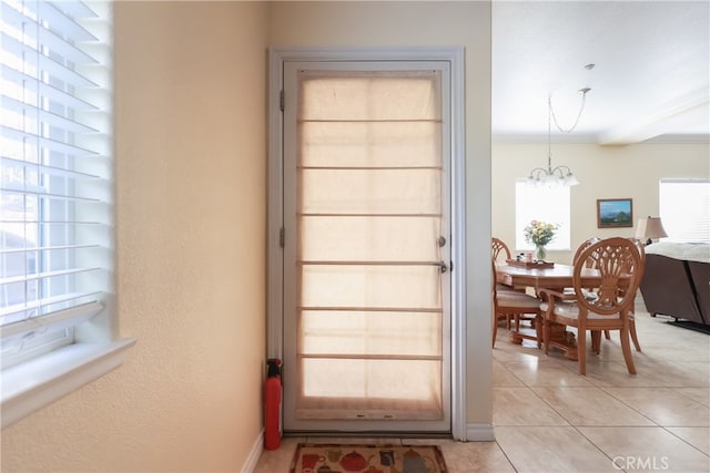 doorway featuring ornamental molding, light tile patterned floors, and a chandelier