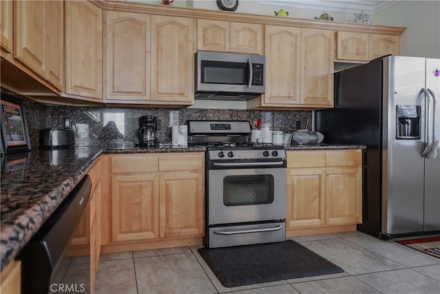 kitchen with light brown cabinetry, appliances with stainless steel finishes, dark stone counters, and backsplash