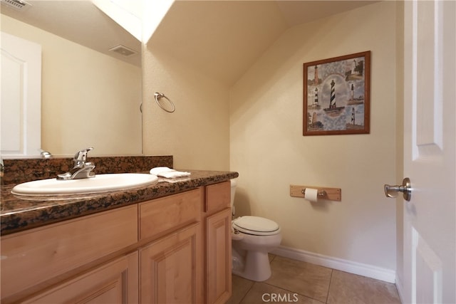 bathroom featuring toilet, vanity, tile patterned floors, and vaulted ceiling