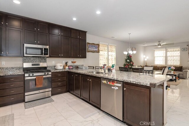 kitchen with decorative light fixtures, sink, kitchen peninsula, and stainless steel appliances