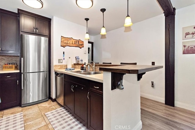 760 Blue Jay Rd Unit 10, Big Bear Lake, CA 92315 - kitchen featuring appliances with stainless steel finishes, a peninsula, a sink, dark brown cabinetry, and pendant lighting