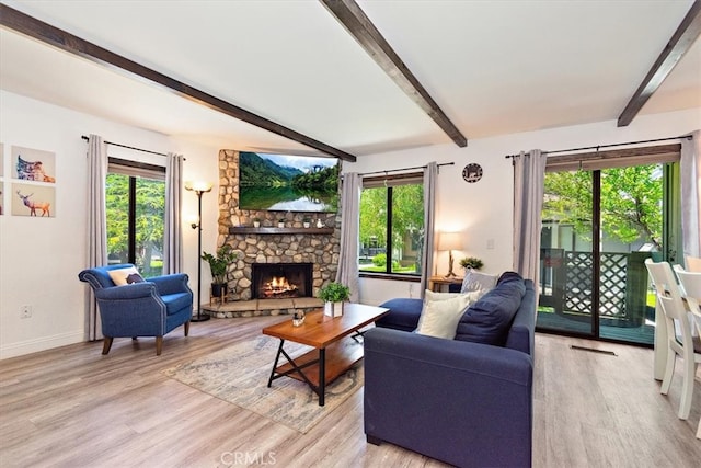 living room featuring a stone fireplace, beamed ceiling, and light hardwood / wood-style flooring