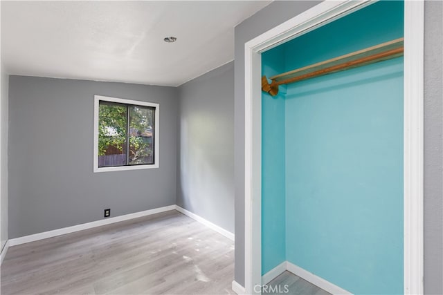 unfurnished bedroom featuring vaulted ceiling, hardwood / wood-style flooring, and a closet