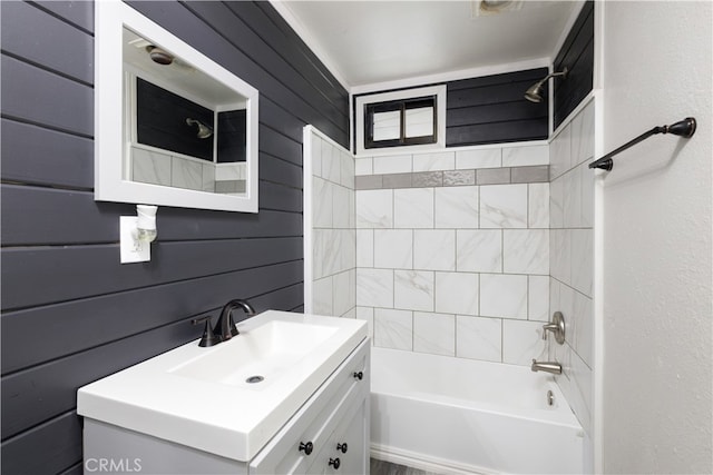 bathroom featuring vanity, wood walls, and tiled shower / bath