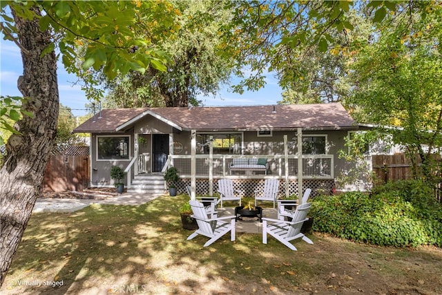 back of house with a fire pit, a wooden deck, and a lawn