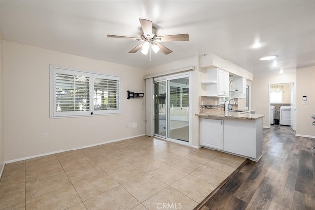 kitchen with independent washer and dryer, white cabinetry, ceiling fan, and light stone counters