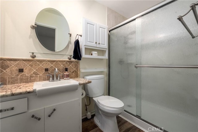 bathroom featuring backsplash, vanity, a shower with door, hardwood / wood-style floors, and toilet